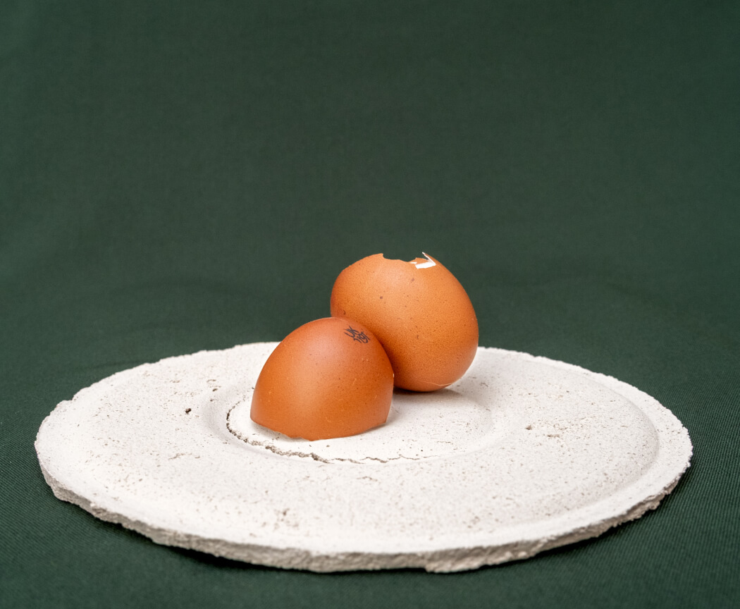 A pair of eggshell halves resting on a handmade bioceramic stand